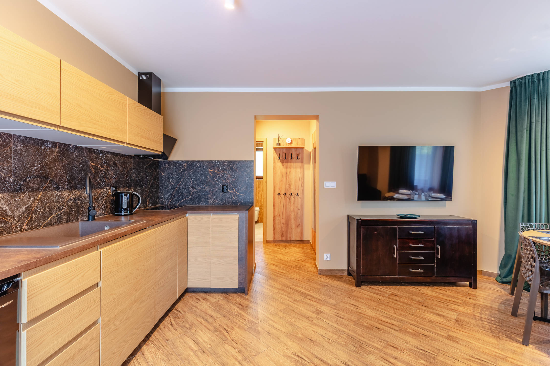 Salon z aneksem kuchennym, telewizorem i stołem w apartamencie.